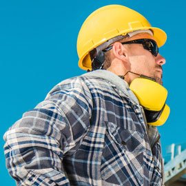 Construction worker with yellow hard hat and earmuffs.